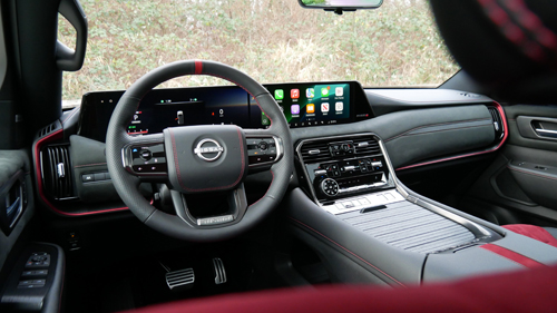 Interior cabin view of the Armada NISMO featuring red Alcantara seat inserts and charcoal leather.