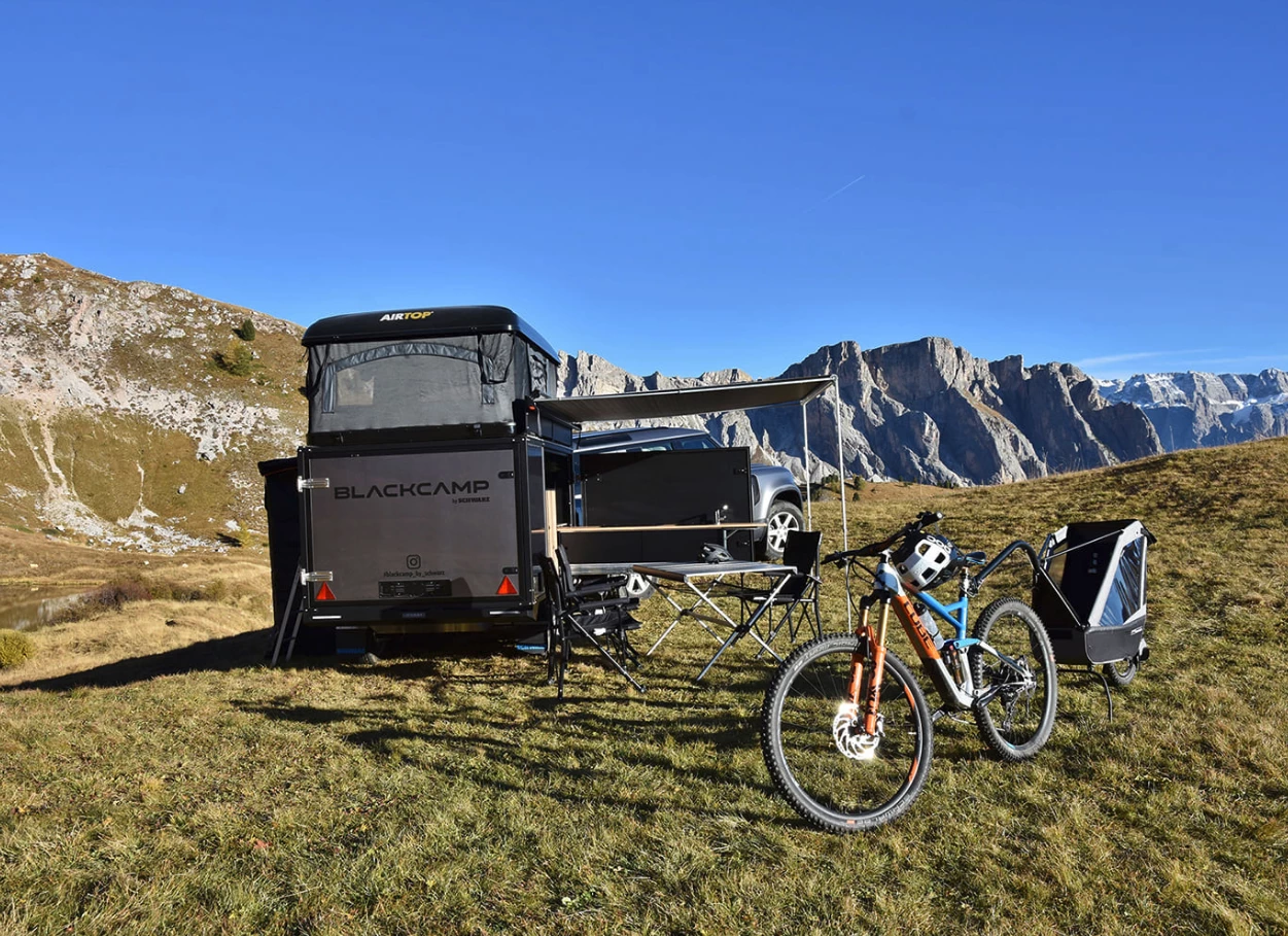 Campers using the Freeda trailer kitchen during a sunset at a campsite