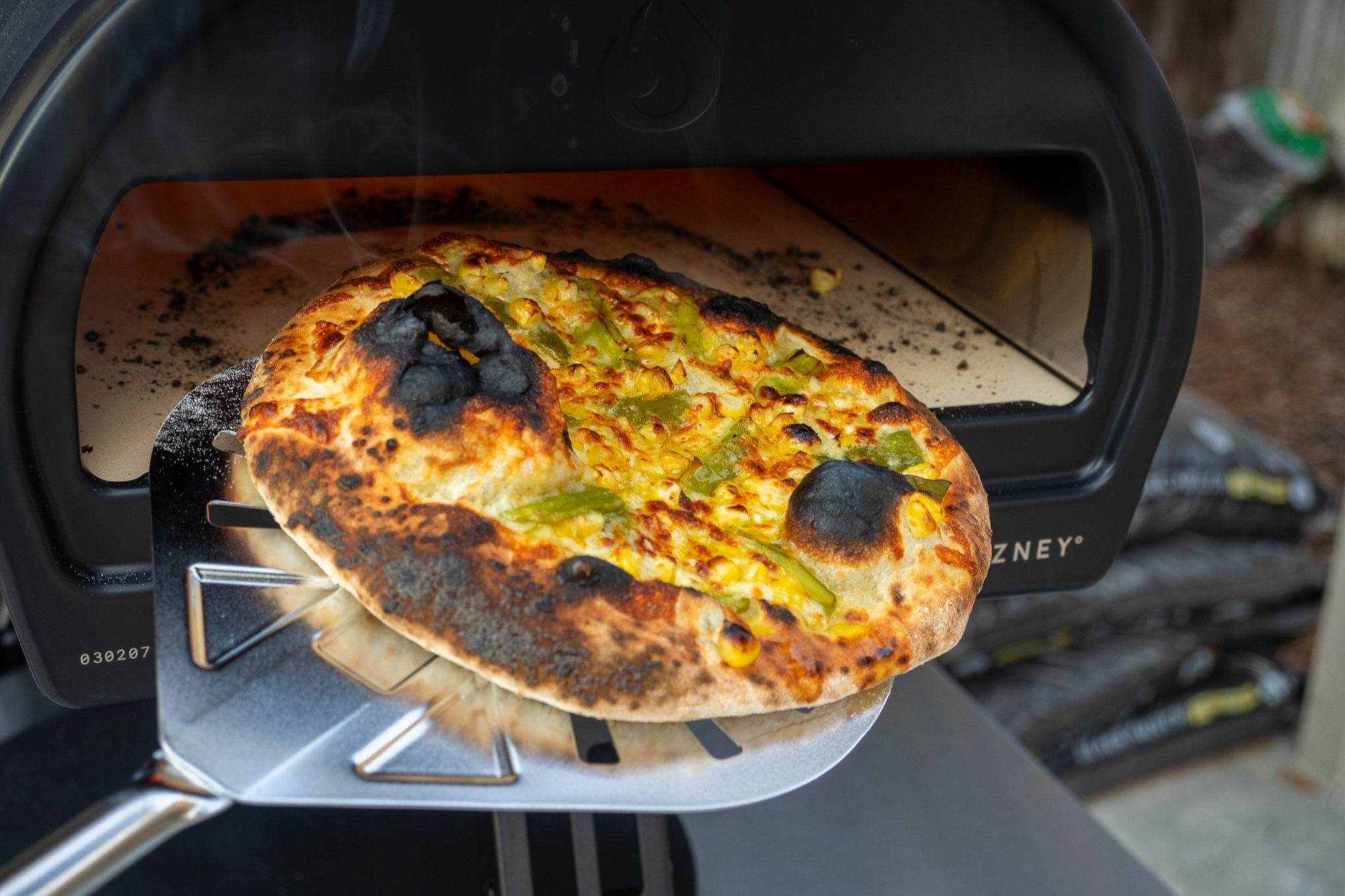 Close-up of a pizza baking inside the glowing orange high-heat chamber of a Roccbox.