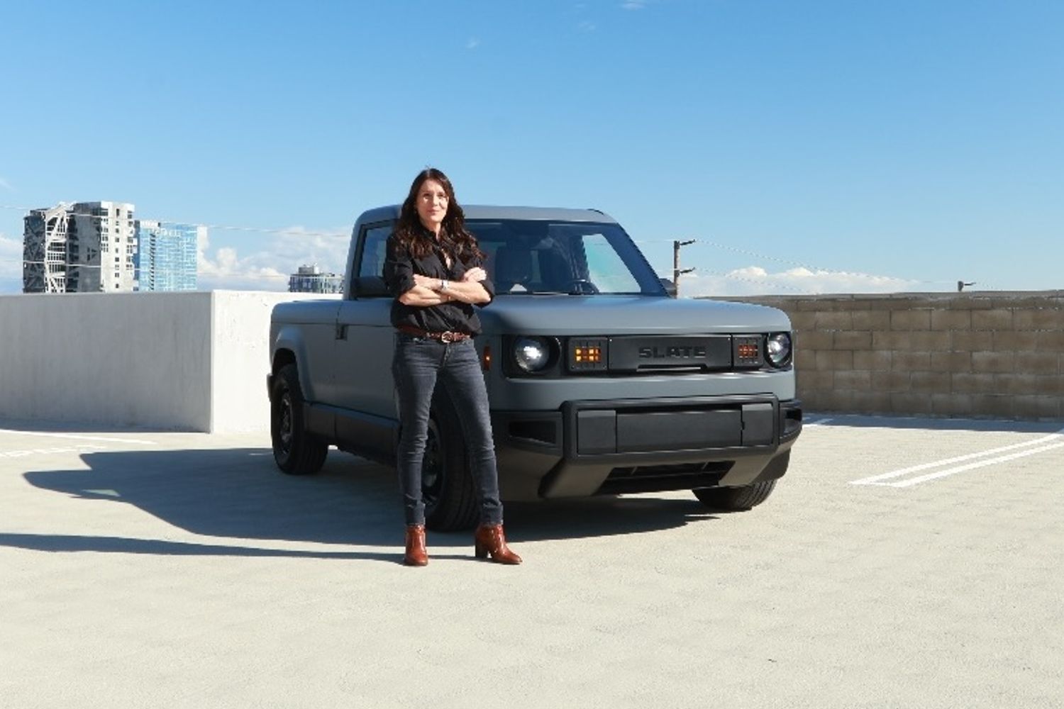 Presenter Ginny Buckley standing next to a silver Slate Auto electric pickup truck.