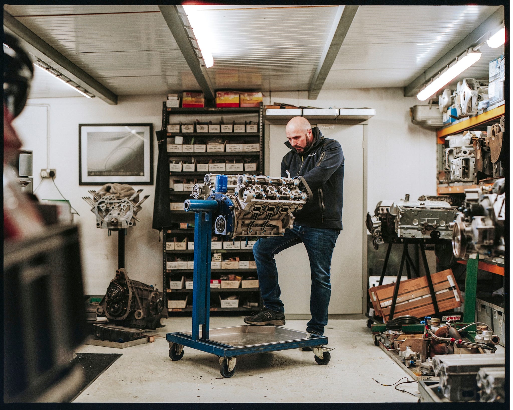 Justin Law working on a Jaguar XJ220 V6 engine on a stand in the workshop.