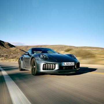 A Jaguar XJ220 driving at speed on a winding mountain road.