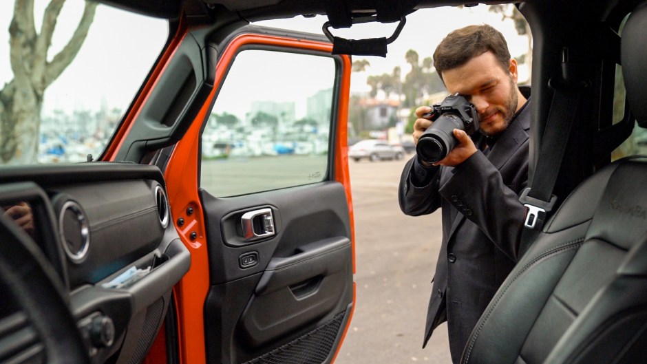 A professional photographer taking detailed photos of a car for an online auction listing.