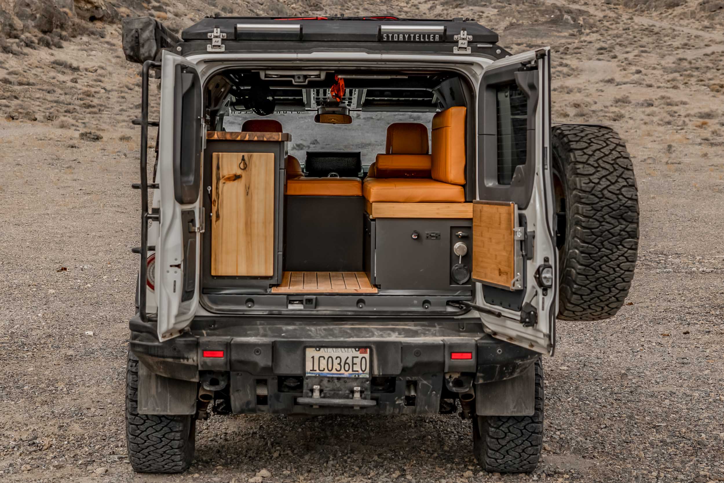 Side profile of the Storyteller Overland Grand Bohemian in a rugged outdoor landscape.