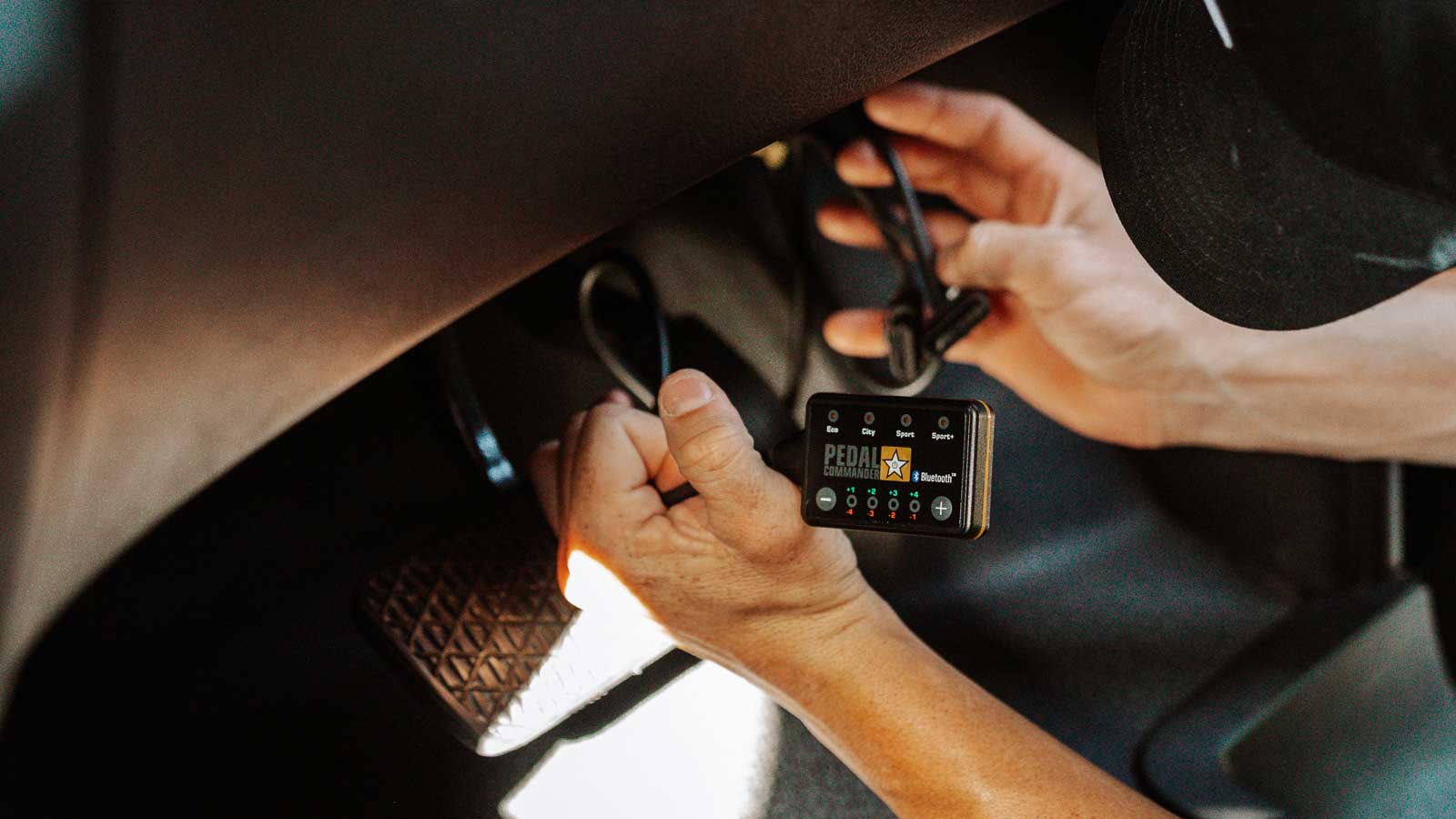 Installation of a Pedal Commander throttle response controller in a Ford truck interior.