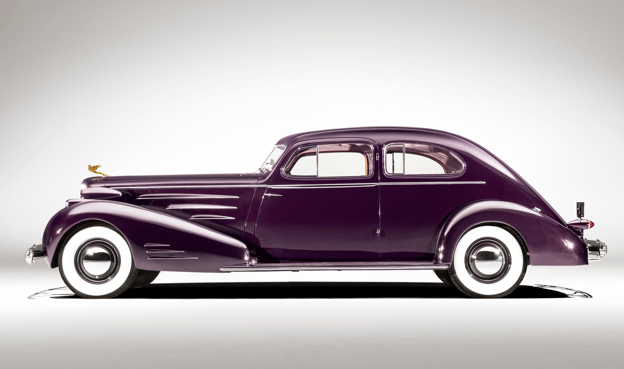 A vintage 1934 Cadillac V-16 Fleetwood aerodynamic coupe in a deep purple finish.