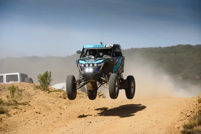 Top three Polaris UTV drivers standing on the podium celebrating their finish.