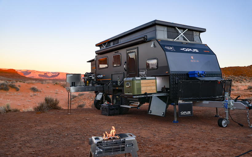Opus off-road camper trailer setup at a campsite in nature.