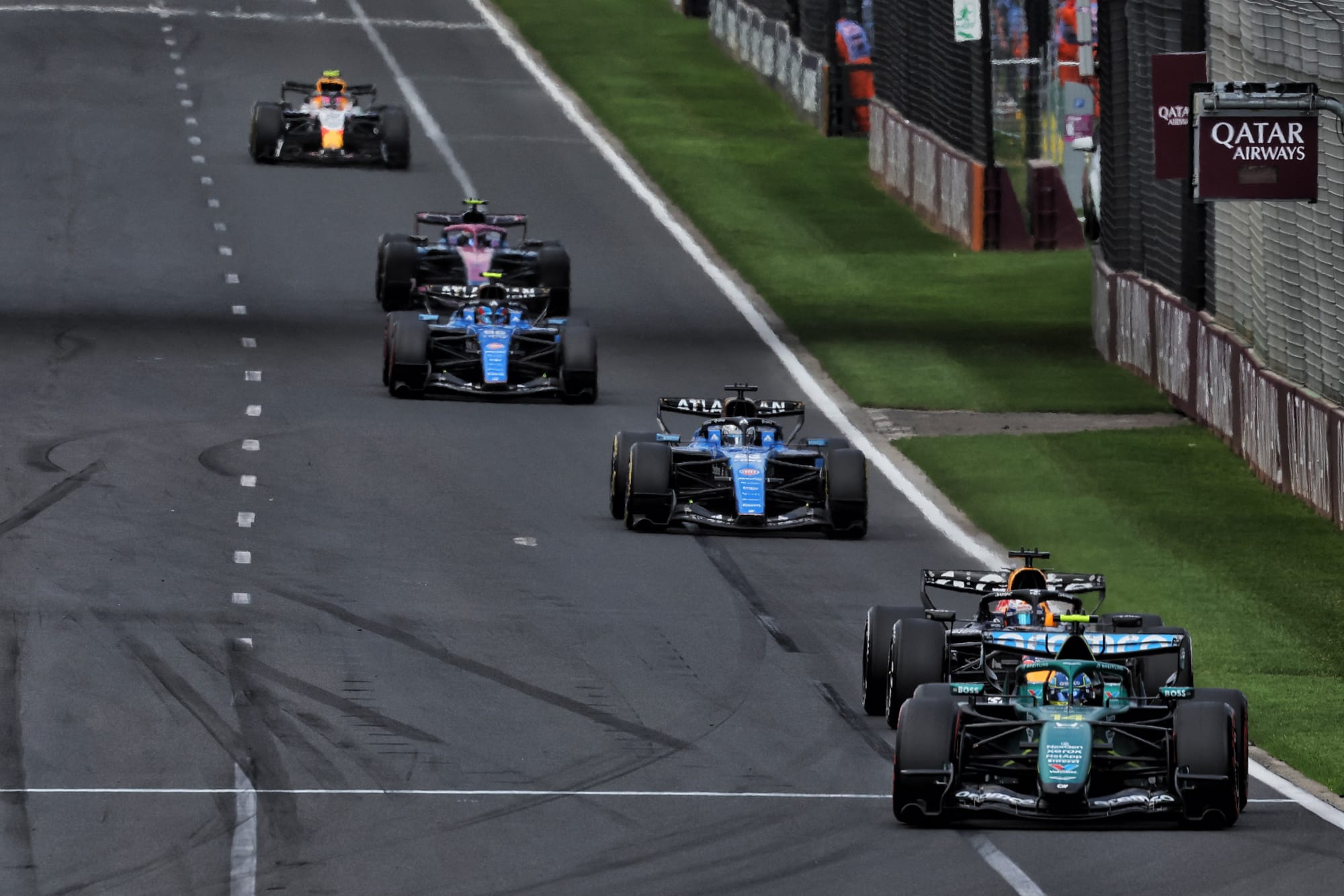 An Aston Martin racing car driving at full speed on a grand prix circuit.