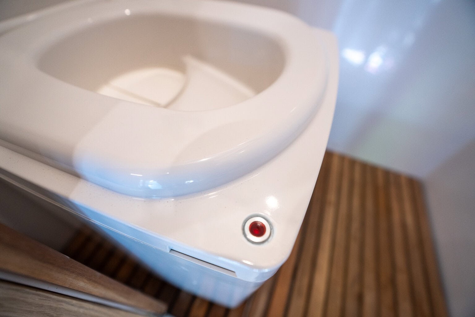 Close-up of the red LED indicator light on the front of the Cuddy Lite toilet.