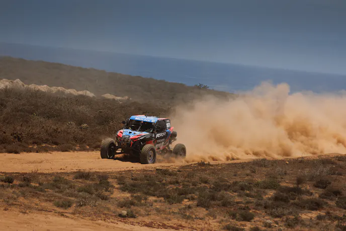 A Polaris UTV navigating the harsh and dusty terrain of the Baja California desert.