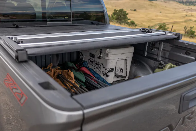 A soft tonneau cover rolled up towards the truck cab, exposing the truck bed.