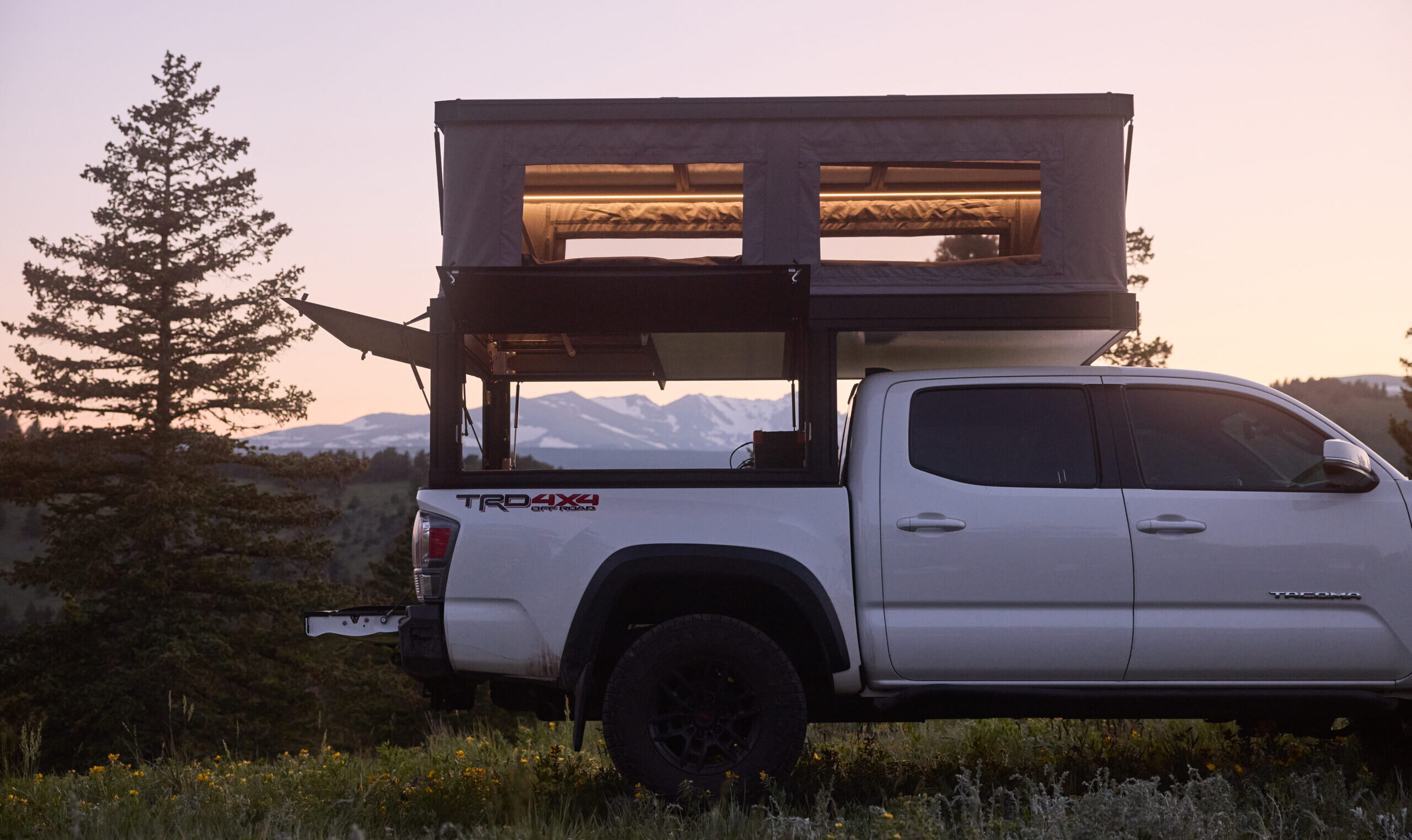 Tune M1Lite truck camper mounted on a white pickup truck in a vast desert landscape.