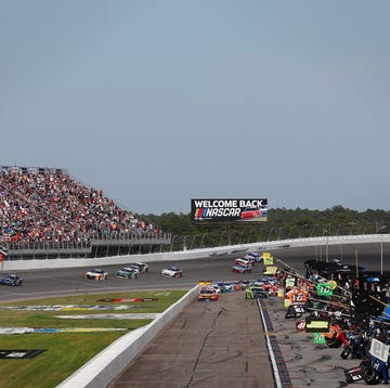 NASCAR race cars competing closely on a paved short track during an Xfinity Series event.