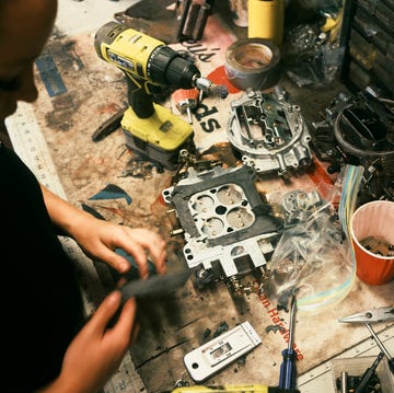 A young mechanic working on a carburetor in a workshop setting.
