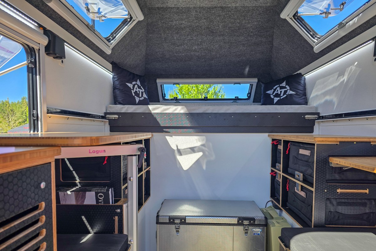 The interior layout of an AT Overland Aterra ASI camper featuring efficient storage and sleeping quarters.