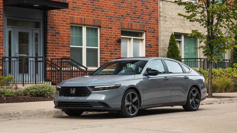 A silver 2025 Honda Accord Hybrid driving on a paved road.