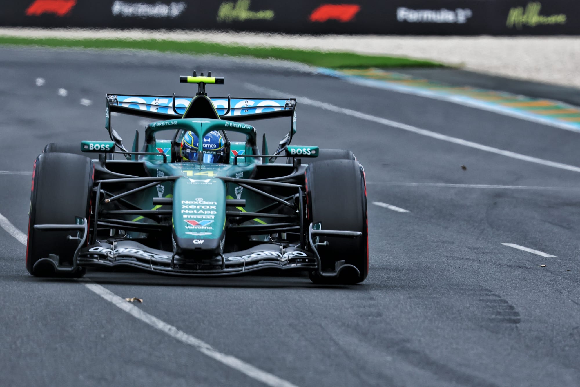 Close-up detail of an Aston Martin F1 car in the garage being serviced by mechanics.