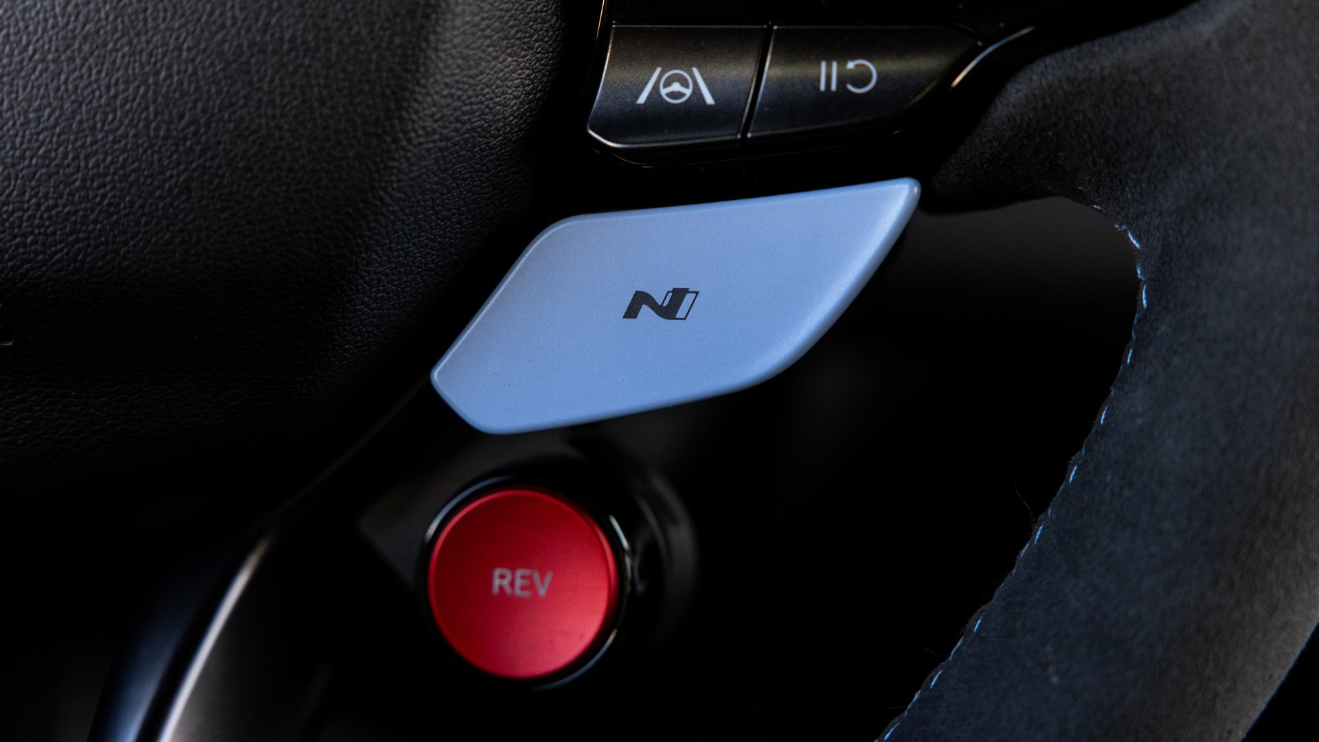 Interior view focusing on the Alcantara-wrapped steering wheel and gear selector.