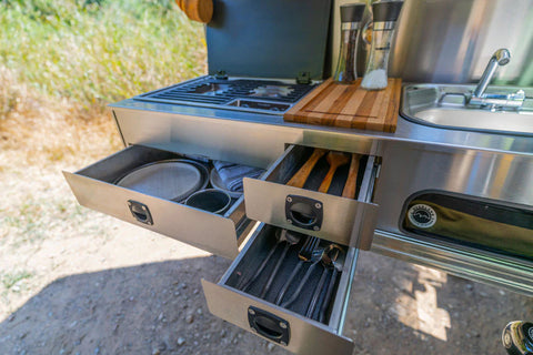 Detailed view of an off-road trailer's slide-out stainless steel kitchen and storage drawers.