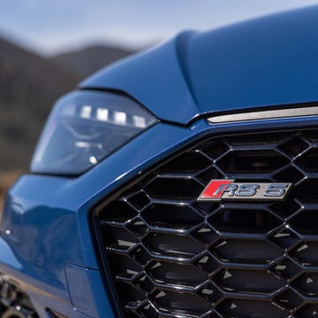A close-up of a blue car's grille featuring an RS 8 emblem.