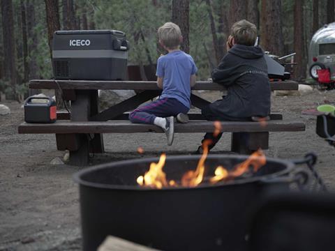 A portable 12V fridge connected to a Jackery lithium power station at a campsite.