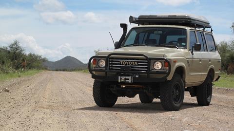 An overlanding Toyota parked on a high ridge overlooking a vast, uninhabited mountain range.