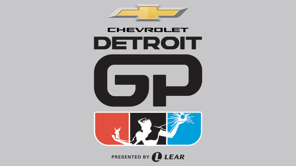 Wide shot of the Detroit Grand Prix street circuit with fans and the city skyline in the background.