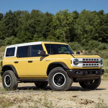 A blue 2023 Ford Bronco Heritage Edition parked in a forest setting.