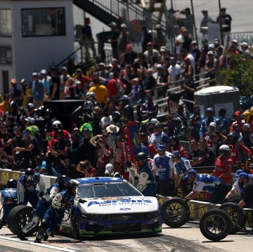 A NASCAR pit crew team performing a high-speed tire change during a race.