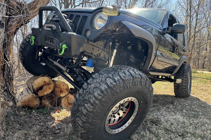 Side profile of a custom Jeep Liberty on a trailer highlighting the lifted suspension and extended wheelbase.