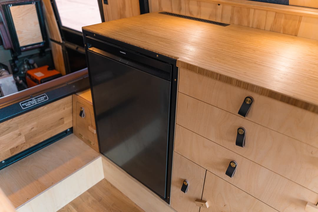 The Volvo 6x6 crossing a shallow river on an Iceland F-road with volcanic mountains in the background.