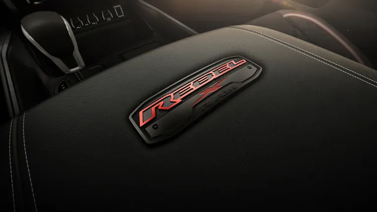 Front view of the 2026 Ram Rebel X kickstarting dust while driving off-road.