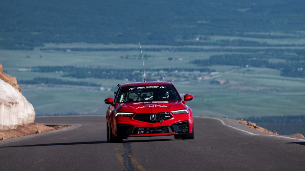 A red performance car driving on a winding mountainous road sequence.