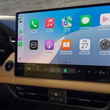 A modern car dashboard featuring a digital touchscreen display integrated with a leather-wrapped steering wheel.