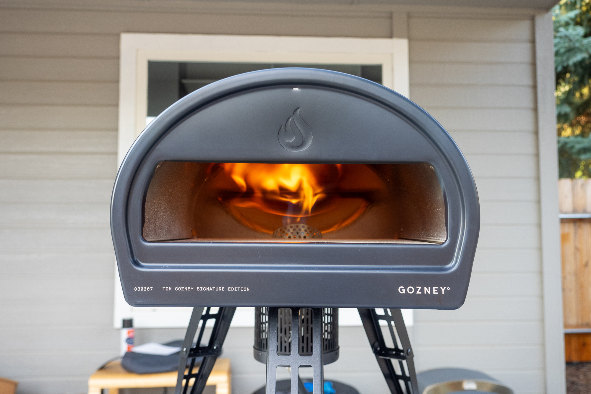 The Gozney Roccbox oven with its gray safe-touch silicone skin and tripod legs extended.