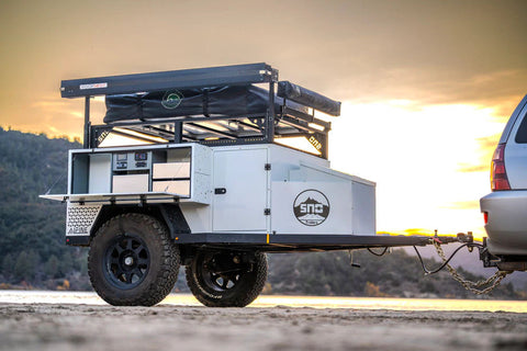 The SNO Trailers Alpine model shown from the passenger side with all-terrain tires and a low profile.