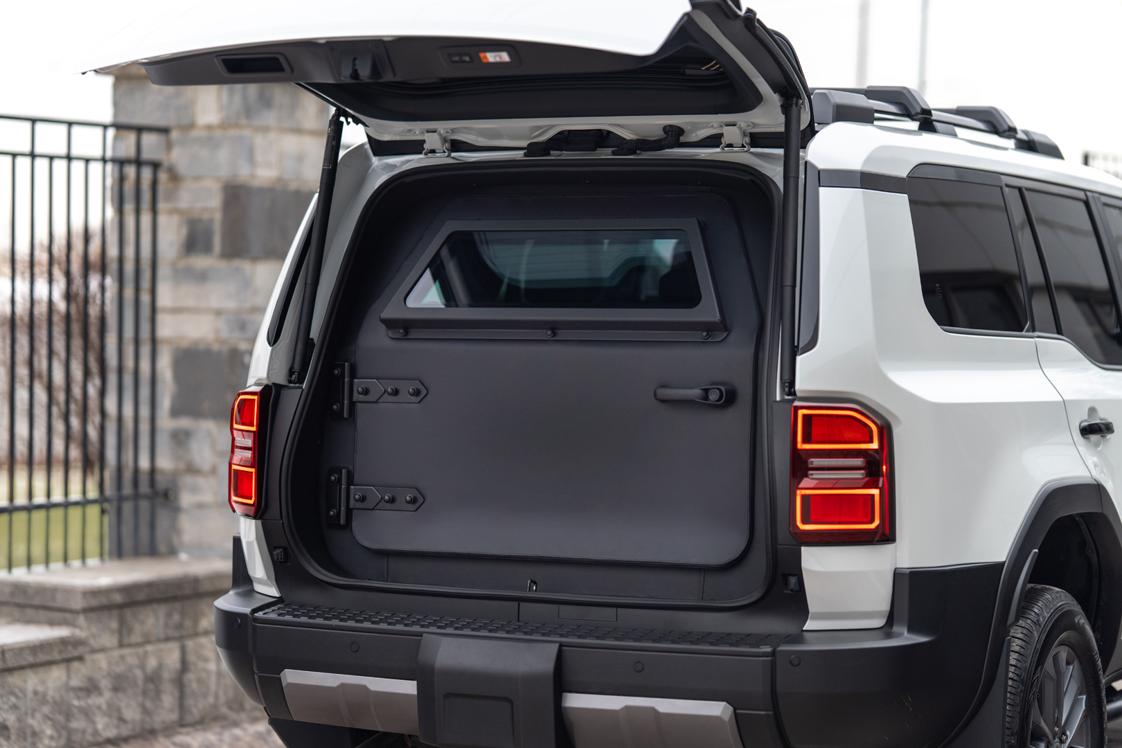 A thick armored inner door positioned behind the standard rear tailgate of a Toyota Land Cruiser.