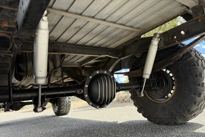 Close-up of the front axle and steering components of a lifted Jeep truck.
