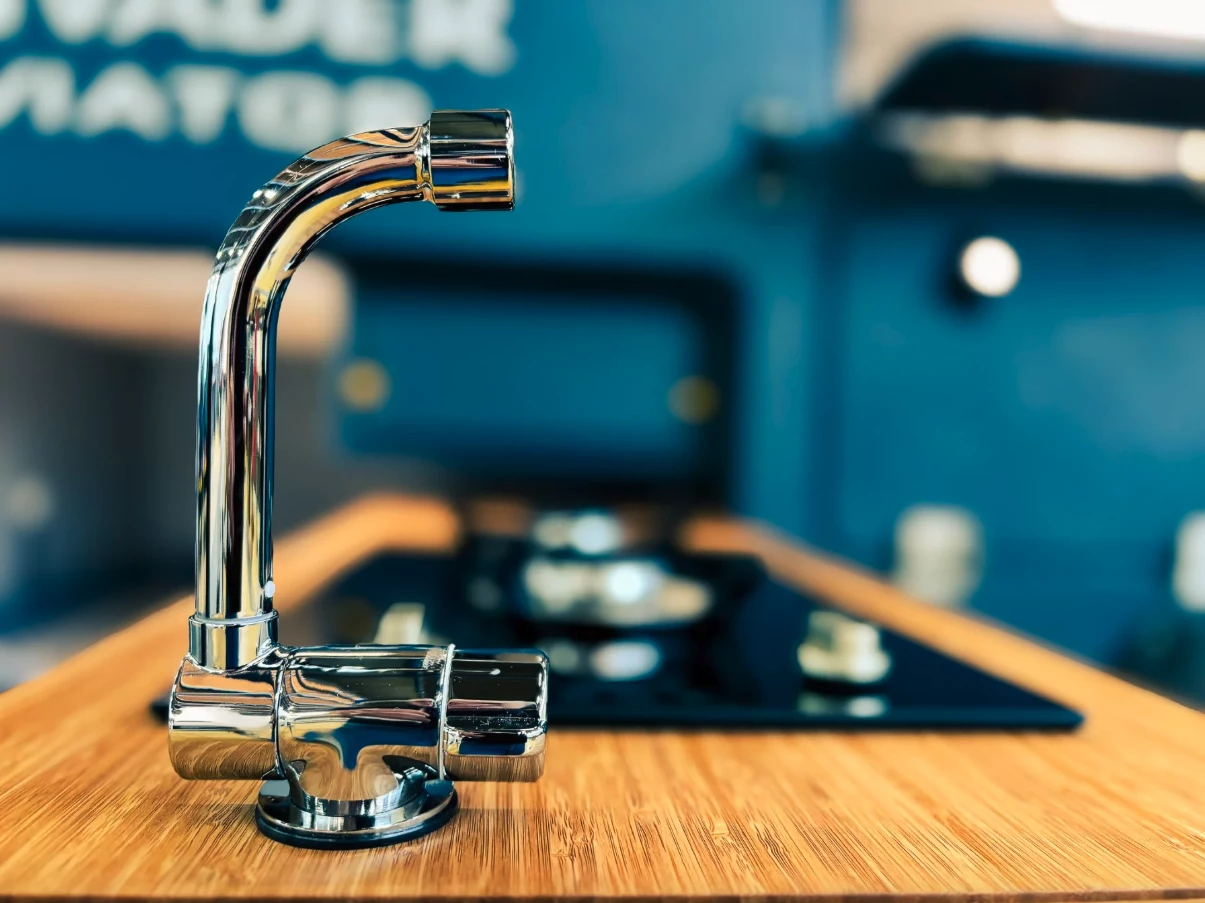 Outdoor slide-out kitchen galley of the Invader Viator featuring a dual-burner stove and integrated sink.