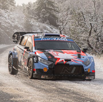 A rally car driving through a snowy mountain pass during the Monte Carlo Rally.